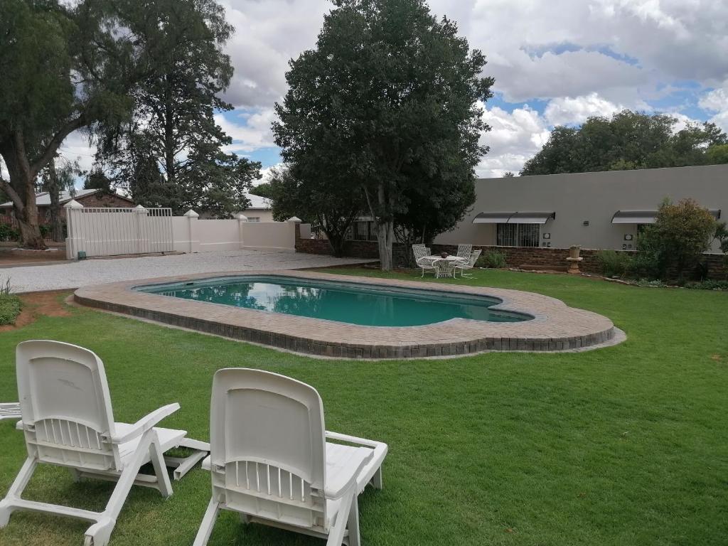 a yard with two chairs and a swimming pool at On Enslin selfcatering in Middelburg