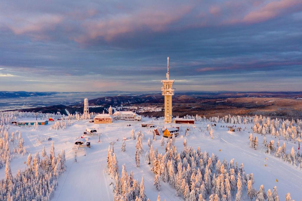 einen schneebedeckten Hügel mit einem Uhrturm in der Ferne in der Unterkunft Chalet Gamma in Jáchymov