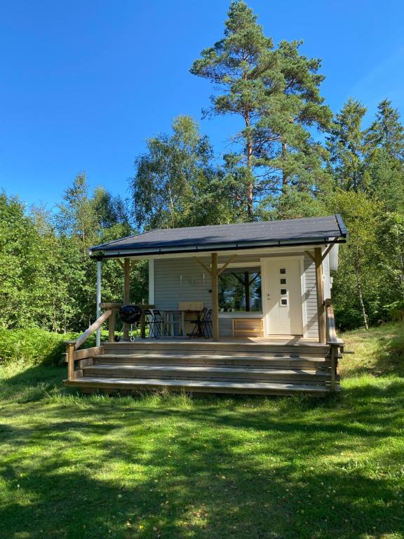 a tiny house with a porch and a deck at Spjutås Gård in Öxabäck