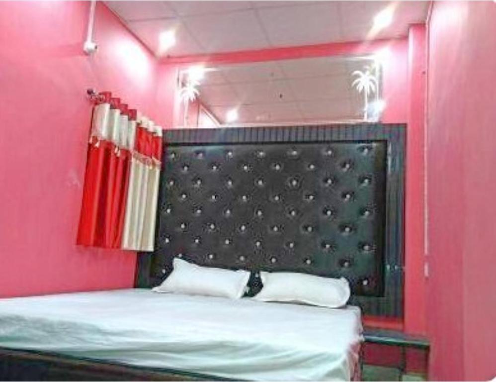 a bed in a pink room with a black headboard at Hotel Good Will, Prayagraj in Muthiganj