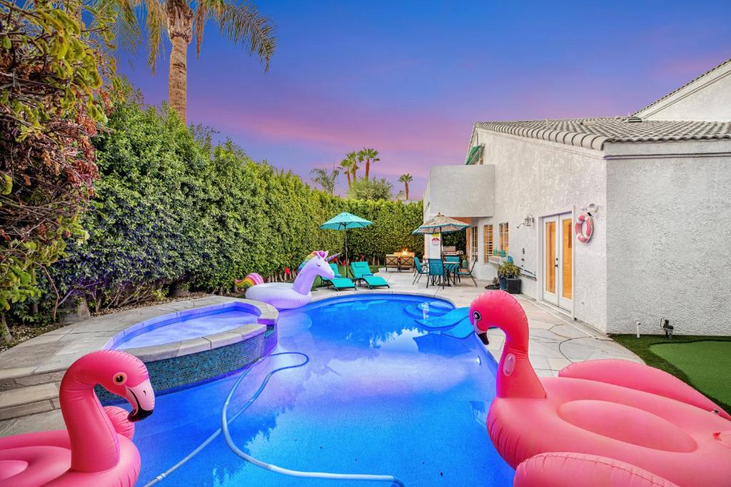 uma piscina com flamingos insufláveis cor-de-rosa num quintal em Carlotta Haven em Palm Desert