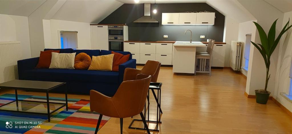 un soggiorno con divano blu e una cucina di Appartement Berendries a Brakel