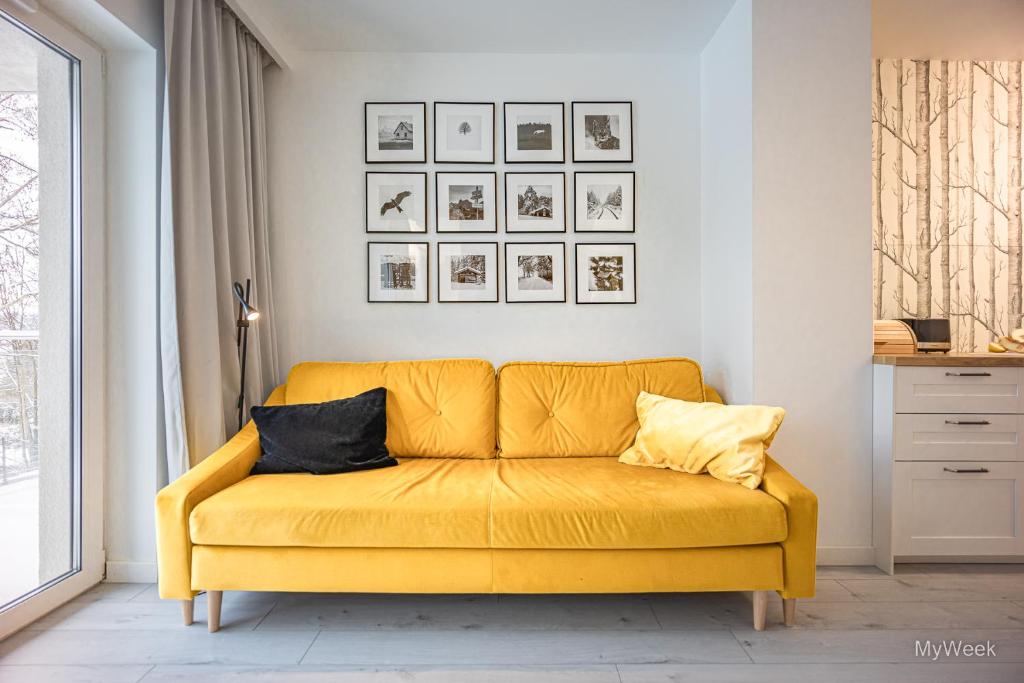 un sofá amarillo en una sala de estar en Apartament z kominkiem.. and SPA, MyWeek, en Polanica-Zdrój