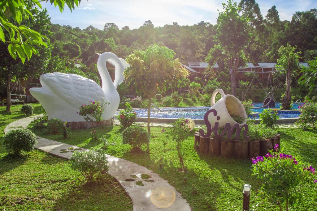 two statues of swans in the grass near a pool at Sim Bungalow in Phú Quốc