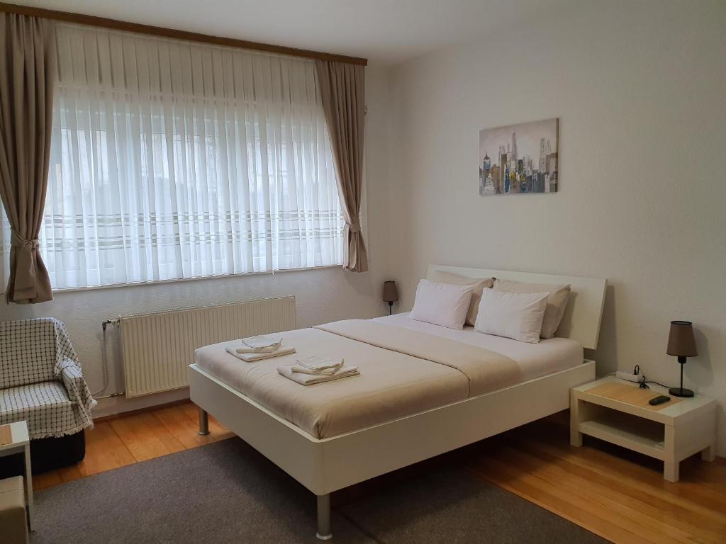 a bedroom with a large white bed and a window at Studio Apartman 11 in Bihać