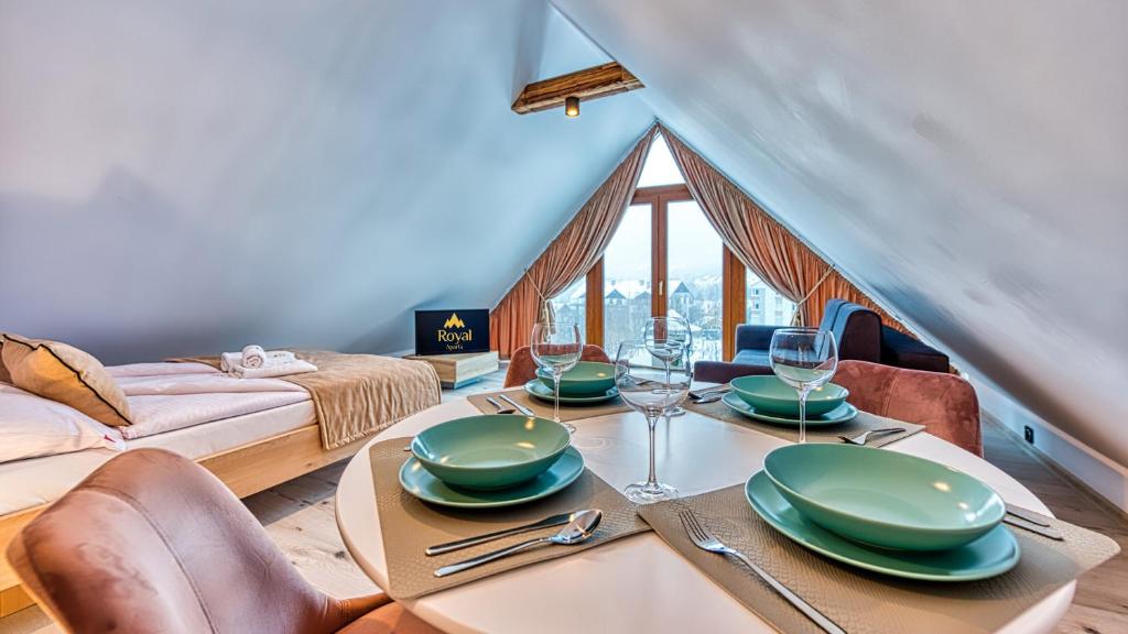 une salle à manger avec une table, des assiettes et des verres à vin dans l'établissement Apartament Cicha 11 VIP z SAUNĄ by Royal Aparts, à Świeradów-Zdrój