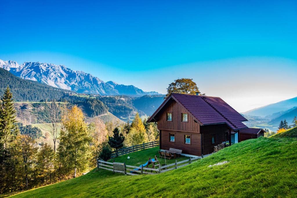 uma casa numa colina com montanhas ao fundo em Ahornhütte em Schladming