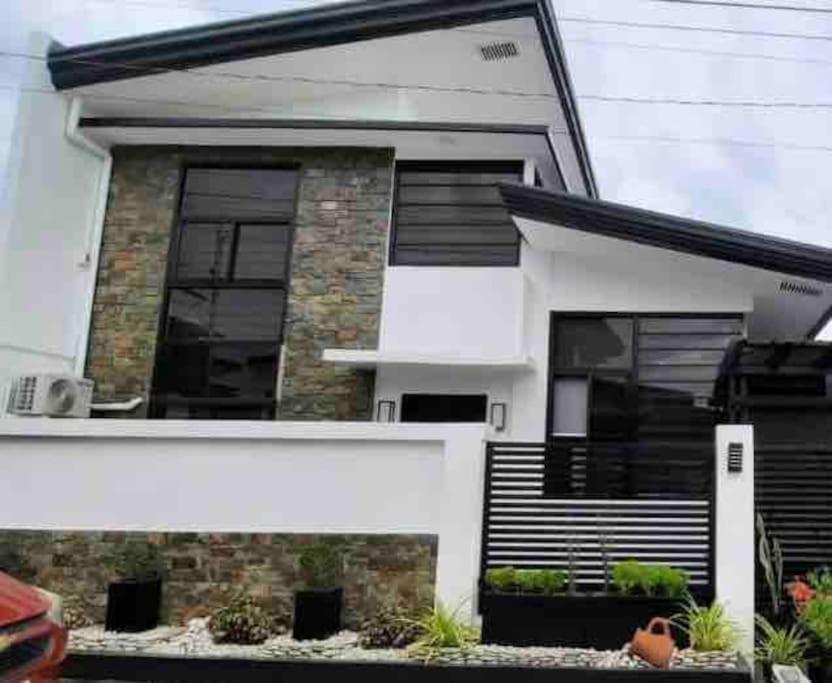 a white house with black shutters on it at Simang’s Guest House in General Santos
