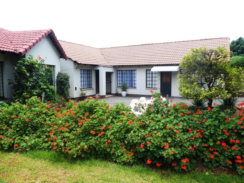 a house with red flowers in the yard at Garden Cottage in Edenvale in Edenvale