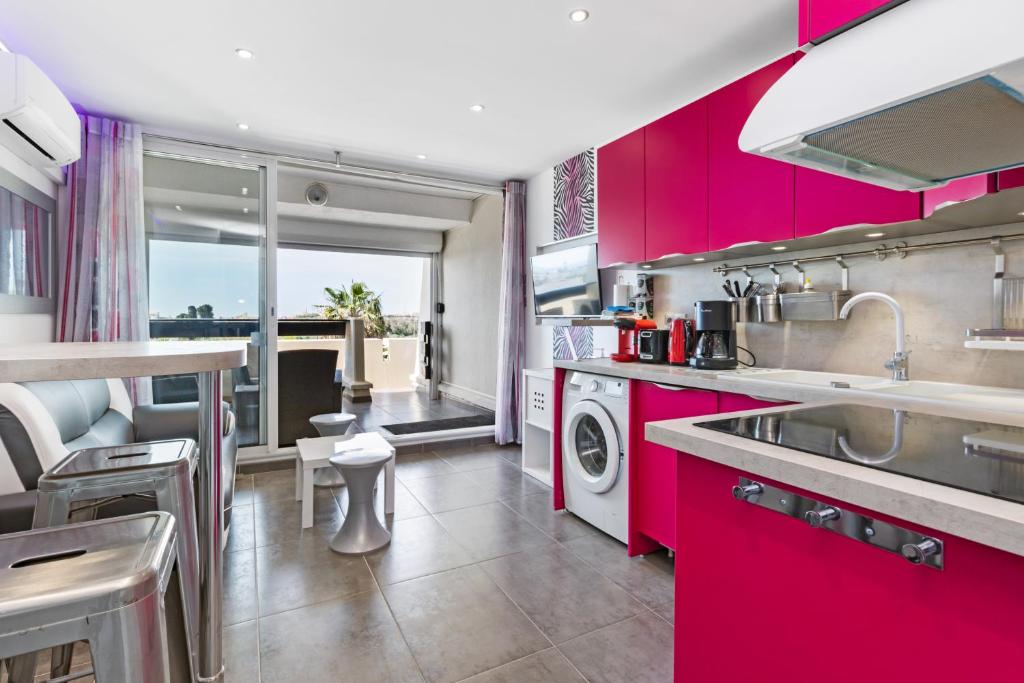 une cuisine avec des armoires rouge vif et un évier dans l'établissement Emplacement N°1 Port Nature 4, coursive vue mer, 2ème étage, village naturiste, au Cap d'Agde