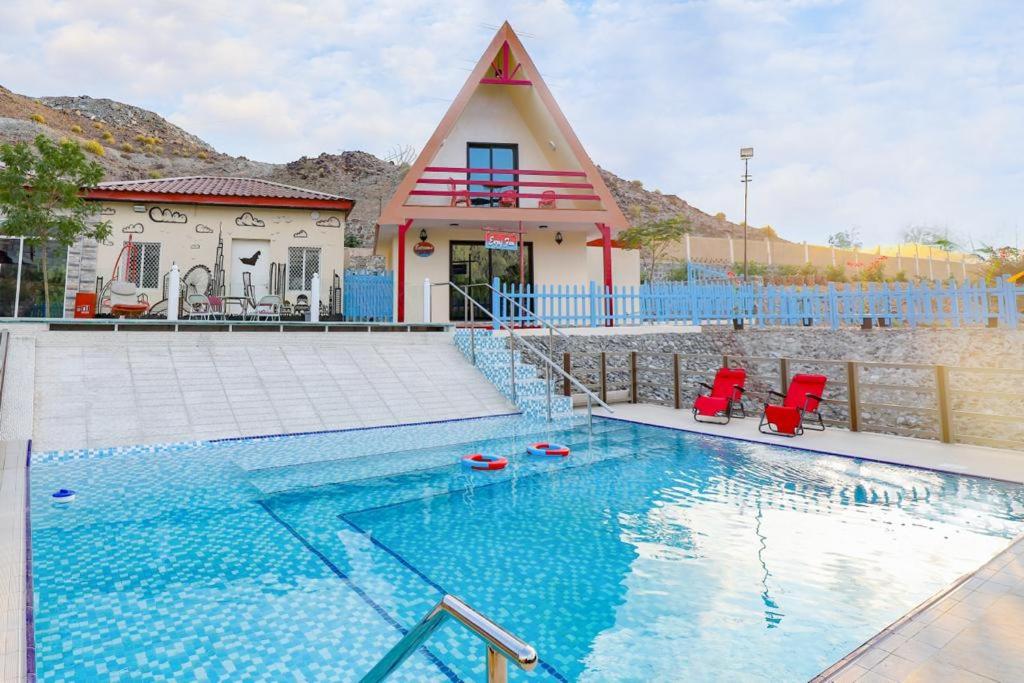 a house with a swimming pool in front of a house at Red_Hut_Resort in Sharīyah