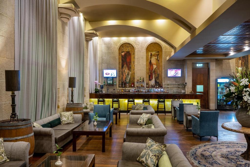 a lobby with couches and a bar in the background at Olive Tree Hotel in Jerusalem