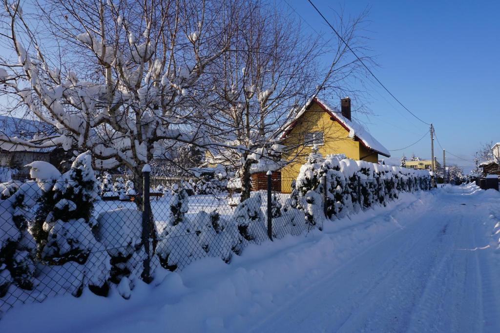 a fence covered in snow next to a house at Uroczy Domek z Kominkiem in Lipowa