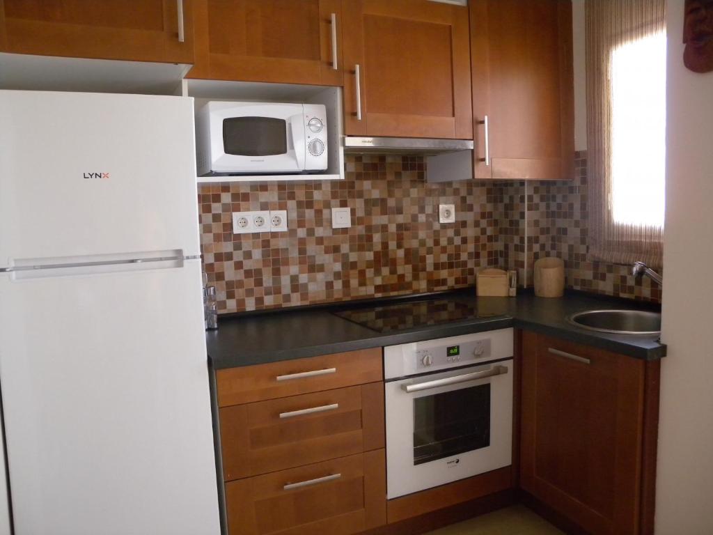 W kuchni znajduje się biała lodówka i kuchenka mikrofalowa. w obiekcie Apartamento Primera Linea de Playa w mieście Oropesa del Mar