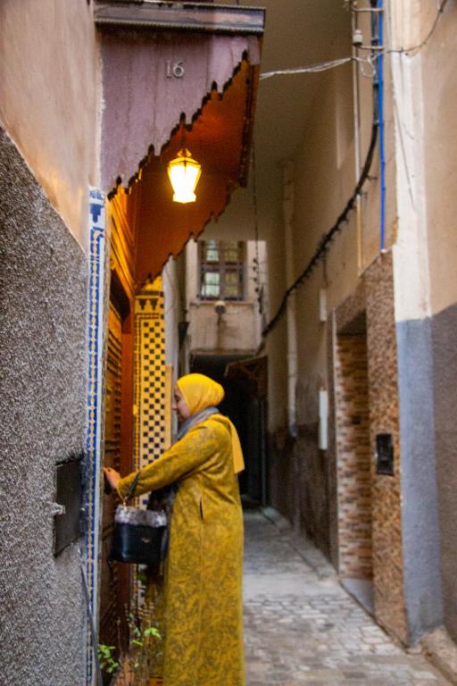 a man in a yellow robe standing in an alley at Riad Baba in Fez