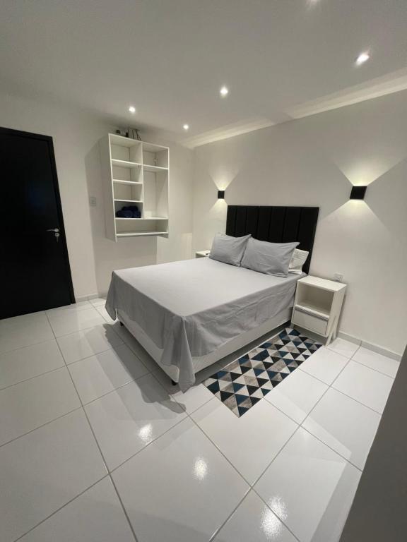 ein weißes Schlafzimmer mit einem Bett und Fliesenboden in der Unterkunft Flat Bugayalê in Garanhuns