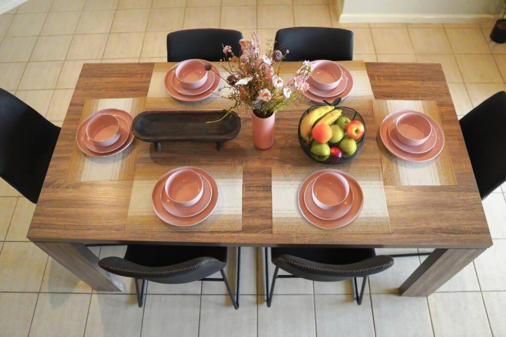 una mesa de madera con platos y un bol de fruta en Top End Marvel -Darwin's Premier 3-BR Luxury Apt en Darwin