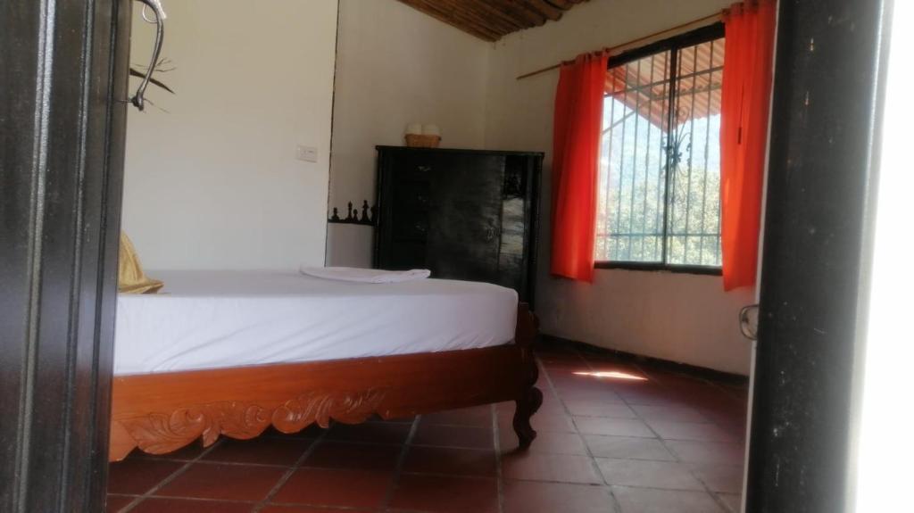 a bedroom with a bed and a window with red curtains at Casa chill out in Minca