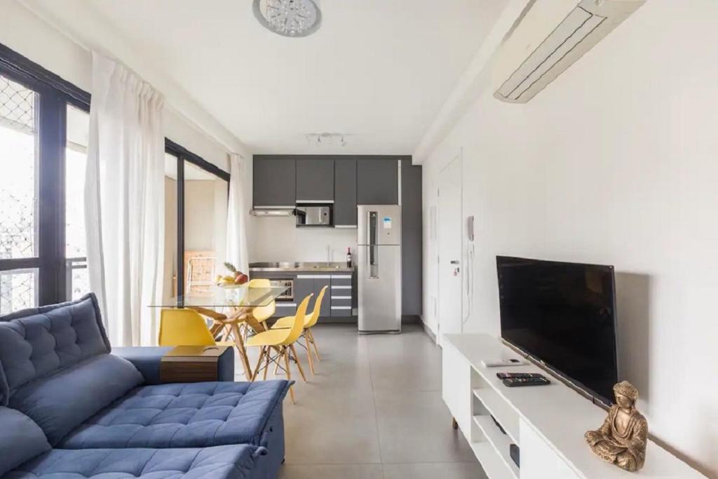聖保羅的住宿－Apartamento em São Paulo, Vila Madalena，一间带蓝色沙发的客厅和一间厨房