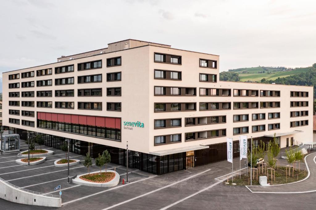 un gran edificio blanco con aparcamiento en Senevita Dorfmatt Ferienwohnungen und Apartments en Münsingen