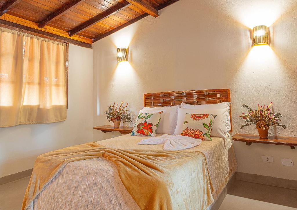 1 dormitorio con 1 cama con 2 almohadas en Kalug - Chalé Chão de Trancoso Studios, en Trancoso