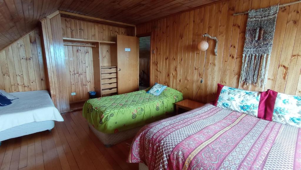 1 dormitorio con 2 camas en una cabaña de madera en Hostal Casa Damasco, en Ancud