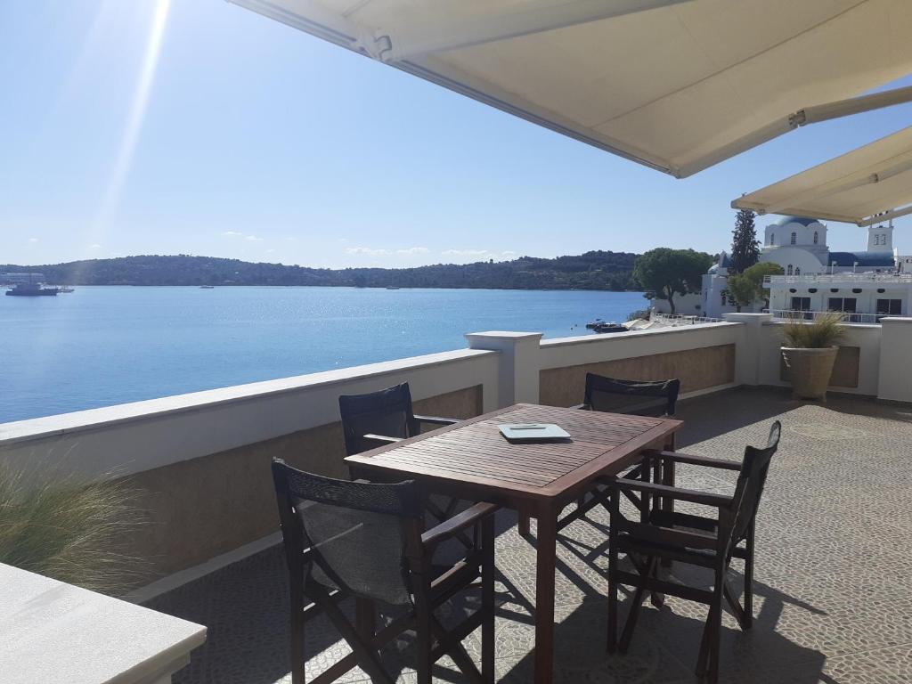 una mesa y sillas en un balcón con vistas al agua en Αξέχαστη διαμονή στο Πορτοχέλι en Porto Heli