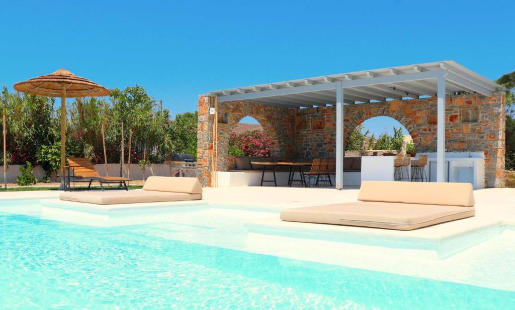 a swimming pool with two beds and an umbrella at The Nine Graces - Kastraki Villas with Private Swimming Pool in Kastraki Naxou