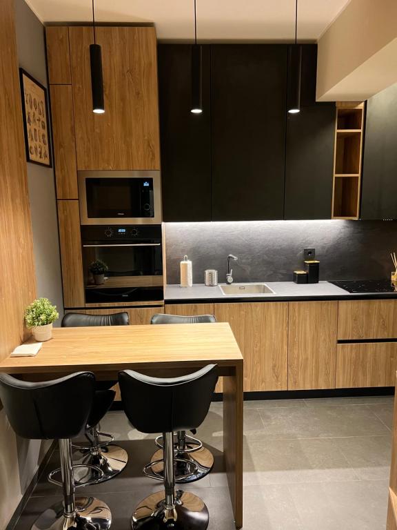a kitchen with a wooden table and some black cabinets at ATH Modern Homes - Luxury Apartment in the City Center in Iaşi