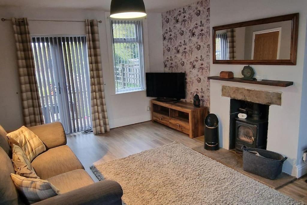 a living room with a couch and a fireplace at Cosy, spacious and comfortable family home. in Kirkburton