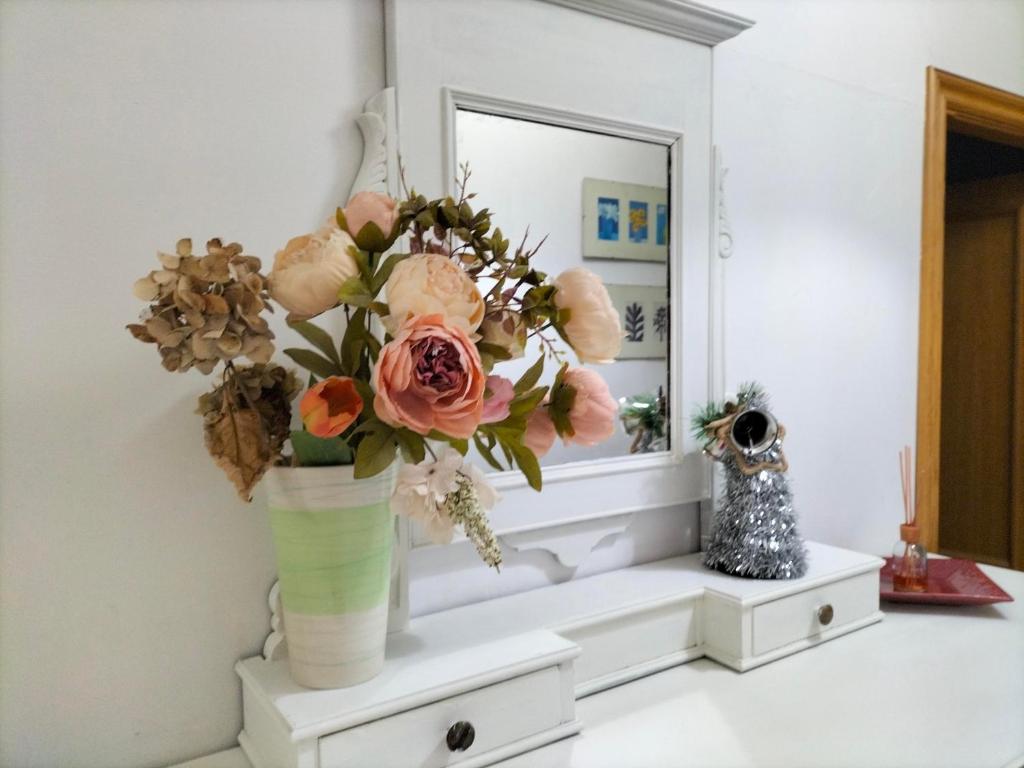un jarrón de flores sentado en un estante frente a un espejo en Appartamento con terrazza in Santa Maria Novella, en Florencia