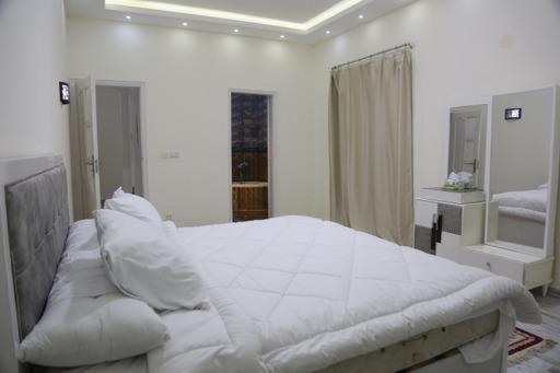 una camera bianca con un grande letto bianco con cuscini di دريم لاند السادس من أكتوبر a Il Cairo