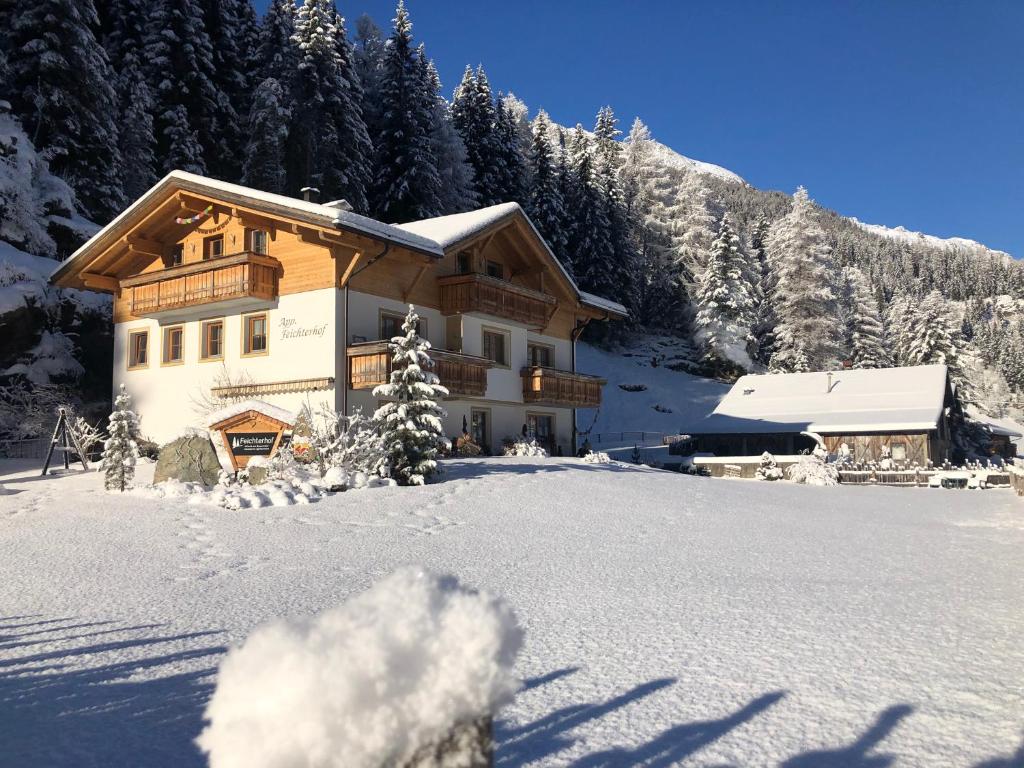 una casa nella neve di fronte a una montagna di Feichterhof a Riva di Tures