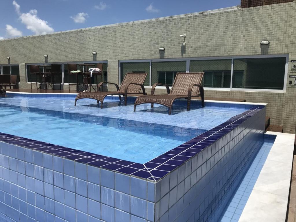 a swimming pool with chairs on top of a building at Flat Beira Mar de Intermares in Cabedelo
