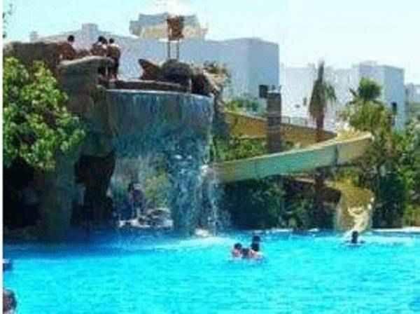 a group of people in a swimming pool with a waterfall at لدينا مكتب عقارات في قرية دلتا شرم We have a real estate office in Delta Sharm in Sharm El Sheikh