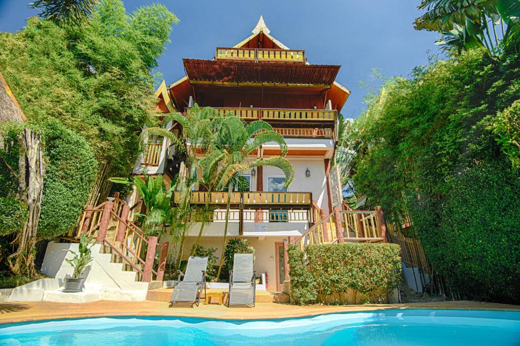 a building with a pool in front of a house at Villa Siam Lanna at Kantiang Bay in Ko Lanta