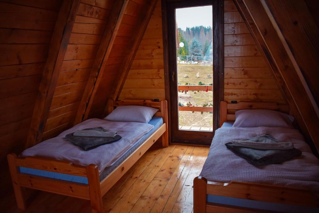 two beds in a log cabin with a window at Vikendica Tromedja Pale in Pale