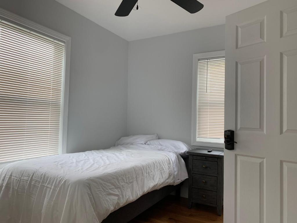 a bedroom with a bed and a dresser and two windows at Twin XL Bed - Boston - RM 1 in Stoneham