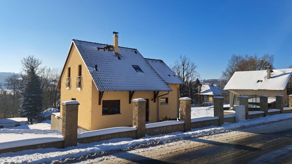 uma pequena casa amarela com uma cerca na neve em Domeček pod skalami, Tisá 535 em Tisá