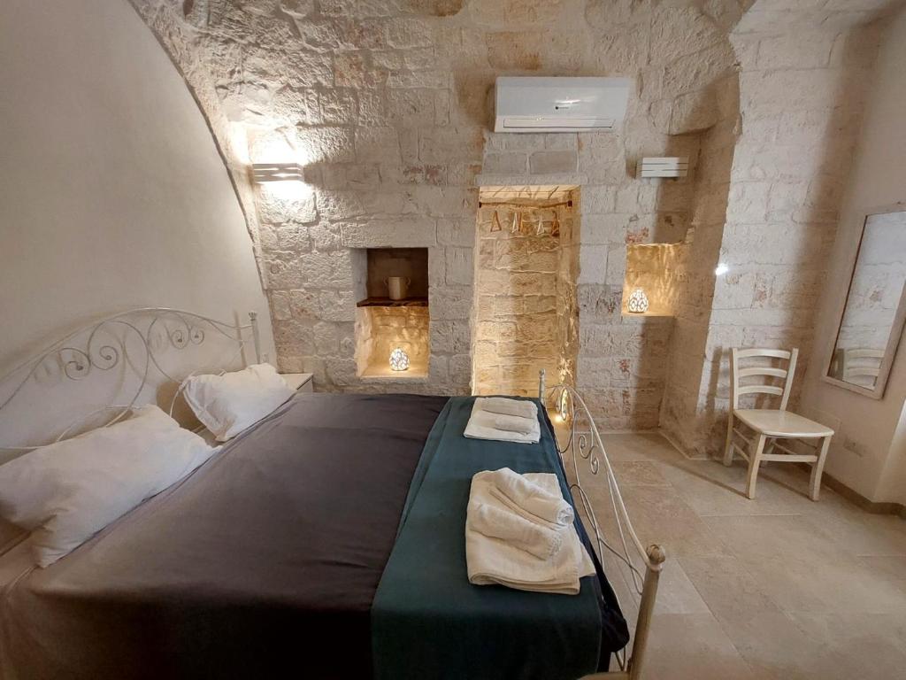 ロコロトンドにあるTrulli Carlo Annaの石壁のベッドルーム1室(大型ベッド1台付)