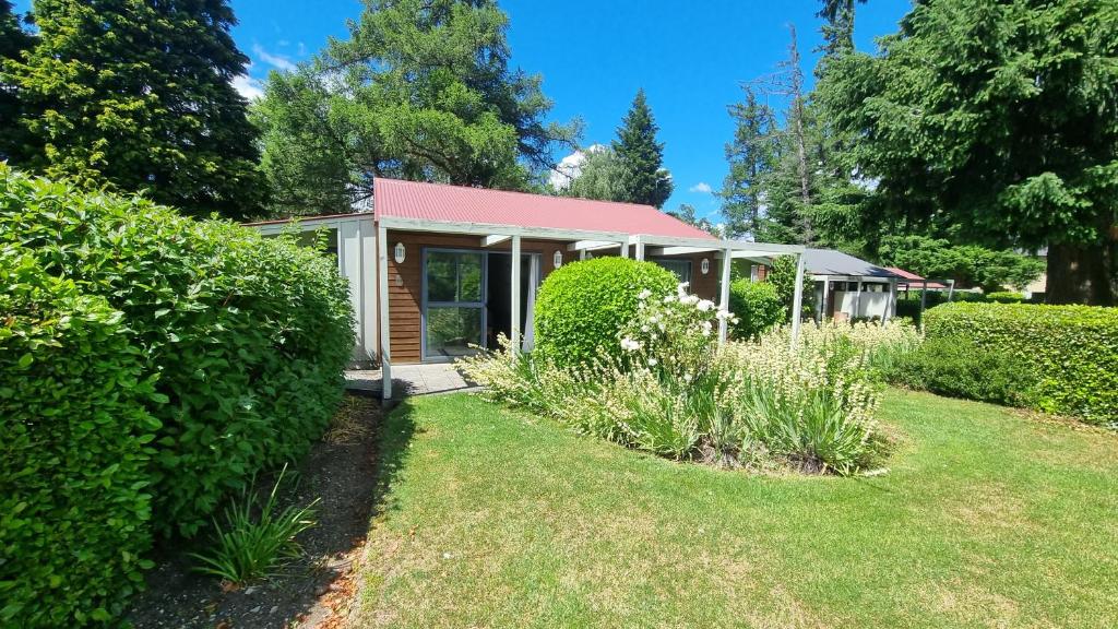 una pequeña casa con techo rojo y patio en 18 Jollies Pass Road - Garden Studio 346, en Hanmer Springs
