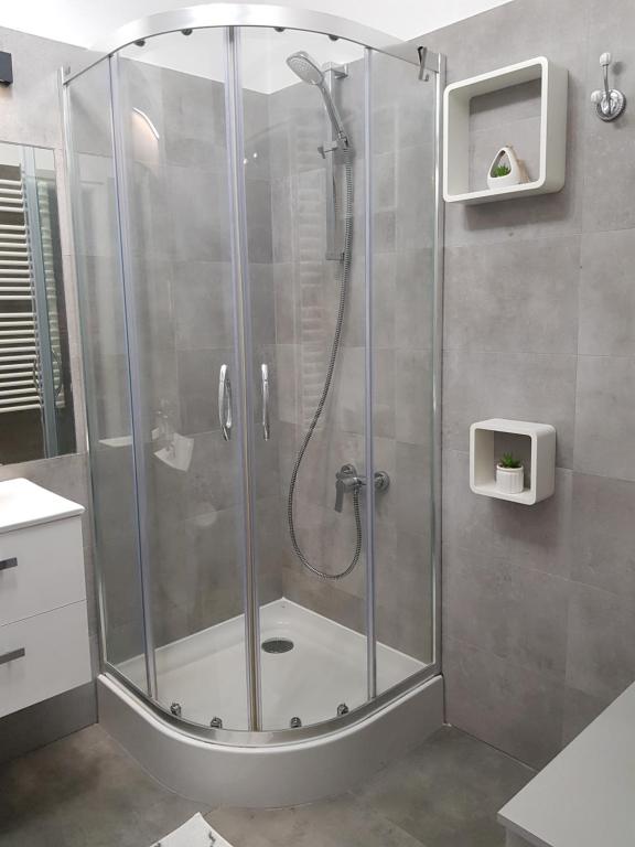 a shower with a glass door in a bathroom at Apartment DAISY, balcony, 5 os, Down Town in Kraków