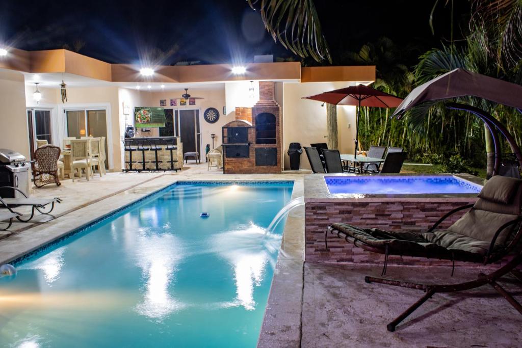 una piscina por la noche con 2 sillas y una sombrilla en Casa Linda beautiful Villa, en Sosúa
