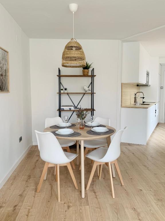 une salle à manger avec une table en bois et des chaises blanches dans l'établissement SAN LORENZO HUESCA con parking, à Huesca