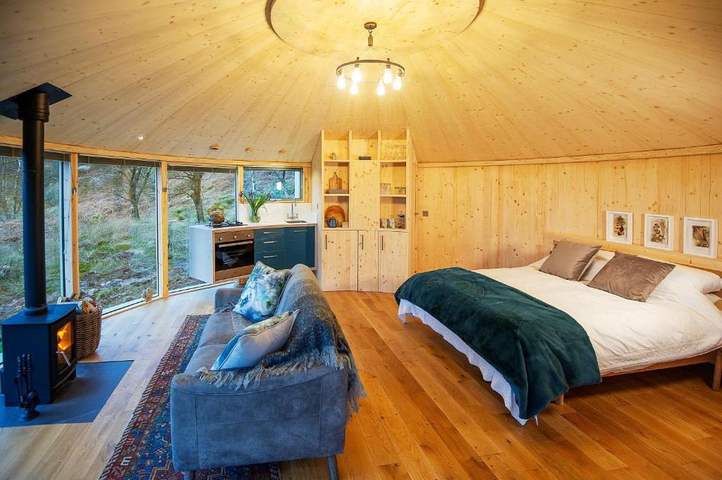 ein Schlafzimmer mit einem Bett und einem Sofa in einem Zimmer in der Unterkunft Luxury romantic Roundhouse and hot tub for two in Glasgow