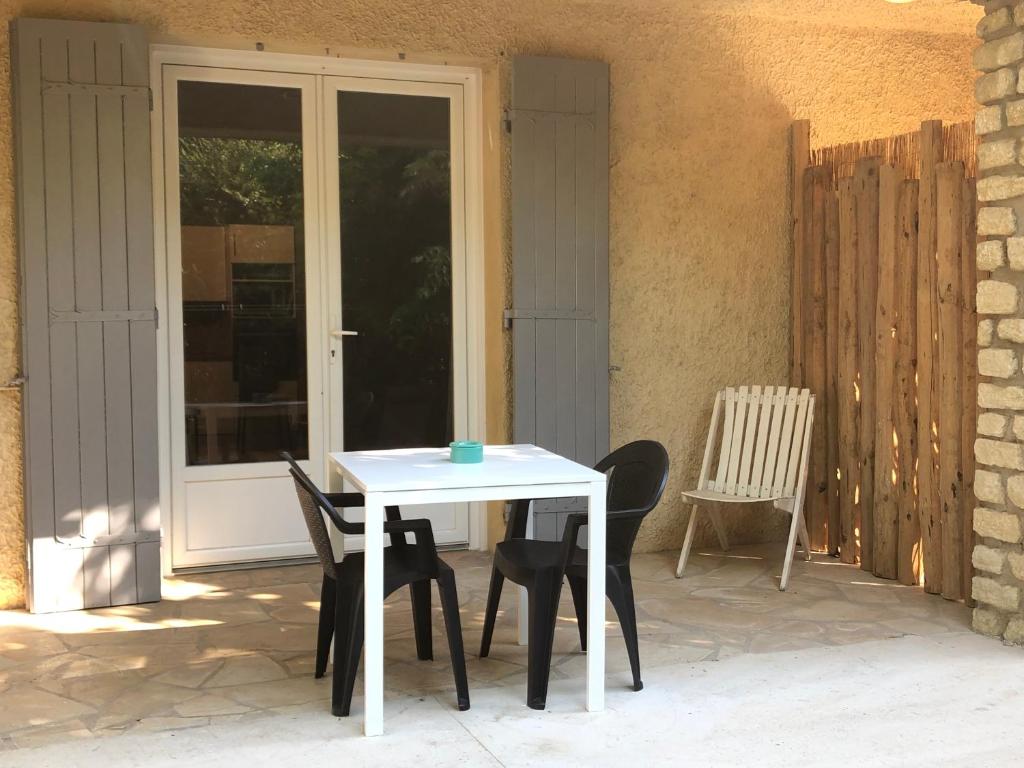 une table blanche et des chaises sur une terrasse dans l'établissement Gîte chez BIBI studio 2 à 4 pers, à Vacqueyras