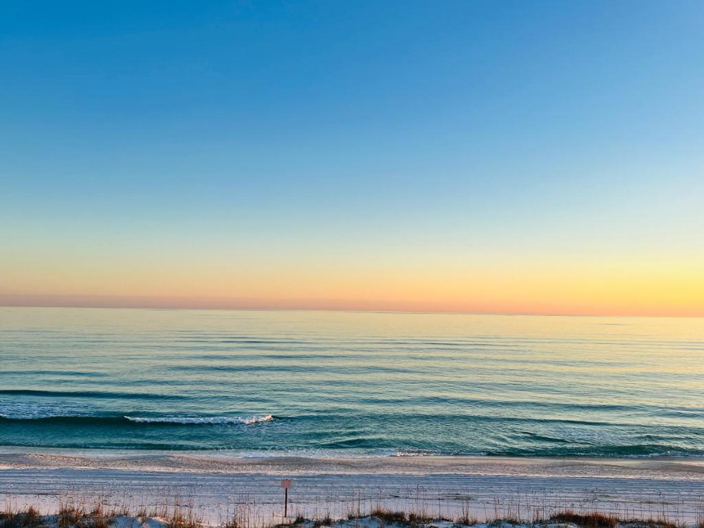 a person riding a wave on the beach at sunset at Gulf Front Penthouse Condo in Pensacola Beach