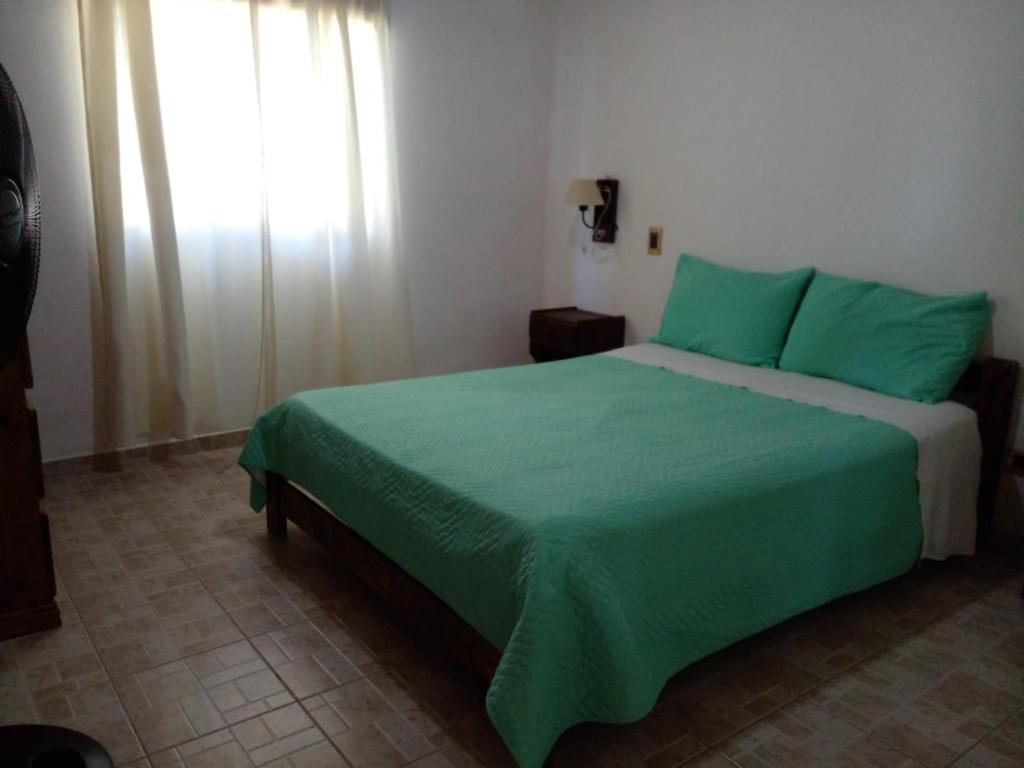 Un dormitorio con una cama con sábanas verdes y una ventana en Cabañas La Soñada en San Rafael