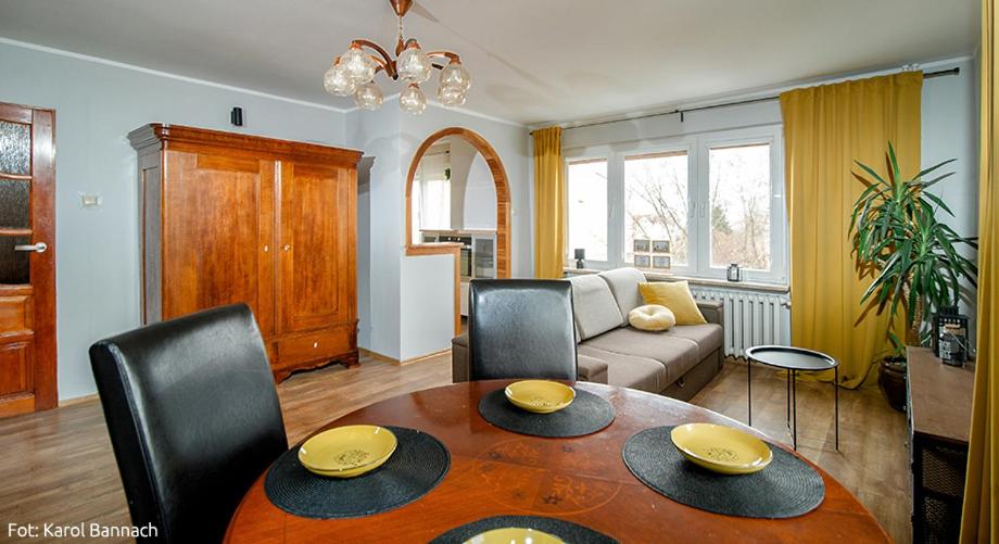 ein Wohnzimmer mit einem Tisch, Stühlen und einem Sofa in der Unterkunft Apartament na Traugutta in Elblag