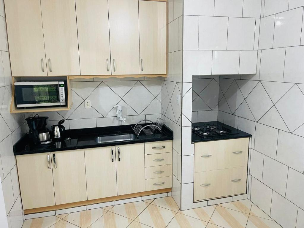 una pequeña cocina con fregadero y microondas en Suites da Rota - Pomerode SC en Pomerode